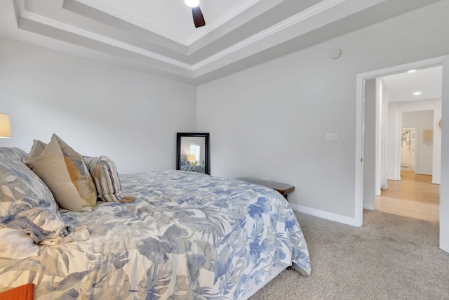 bedroom with crown molding, carpet floors, a ceiling fan, and a raised ceiling