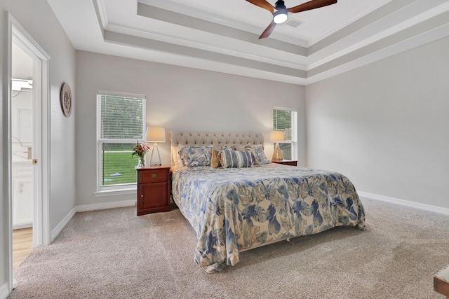 carpeted bedroom with crown molding, baseboards, ensuite bath, and a tray ceiling