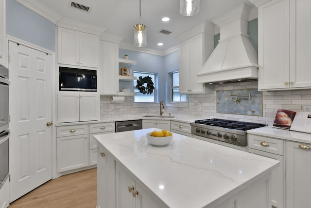 kitchen featuring appliances with stainless steel finishes, a sink, white cabinetry, custom range hood, and visible vents