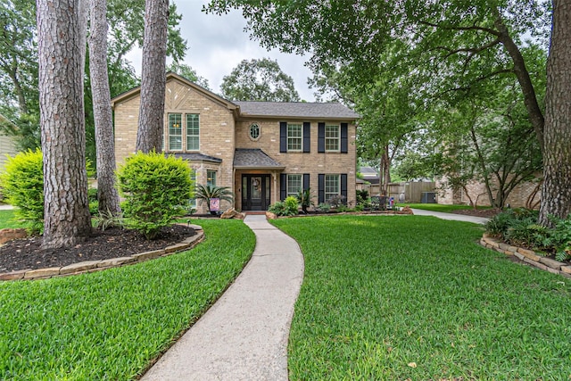 traditional home featuring brick siding, fence, and a front lawn