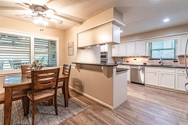 kitchen featuring stainless steel dishwasher, a sink, a textured ceiling, and a kitchen bar