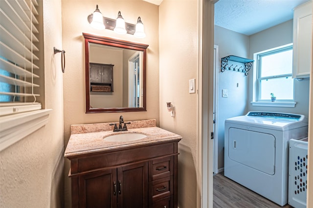 bathroom with separate washer and dryer, a textured wall, wood finished floors, and vanity