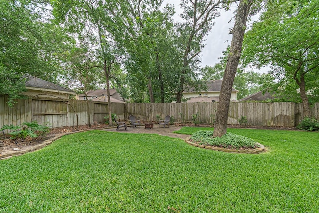 view of yard with a fenced backyard, a fire pit, and a patio area