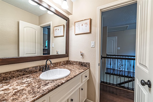 bathroom with vanity, a textured wall, and wood finished floors