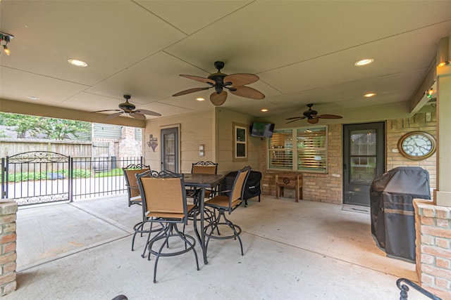 view of patio with ceiling fan, fence, outdoor dining space, and a grill