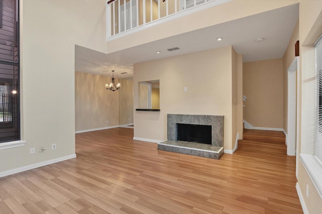 7447 Cambridge St, Houston, TX 77054 - unfurnished living room with a premium fireplace, a chandelier, light wood finished floors, baseboards, and a towering ceiling