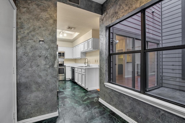 7447 Cambridge St, Houston, TX 77054 - kitchen with a sink, appliances with stainless steel finishes, dark marble finish flooring, white cabinetry, and light countertops