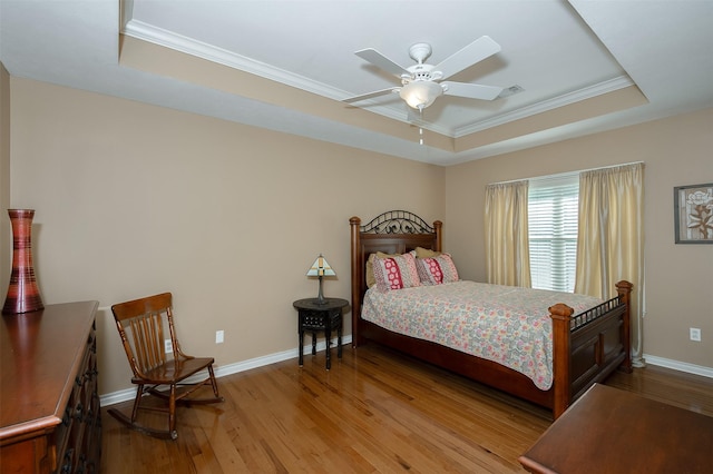 bedroom featuring crown molding, visible vents, baseboards, a tray ceiling, and light wood finished floors