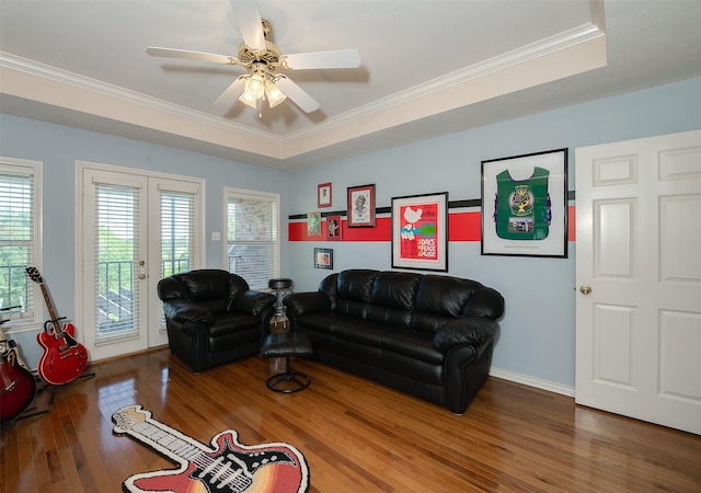 living area with crown molding, ceiling fan, a raised ceiling, french doors, and wood finished floors
