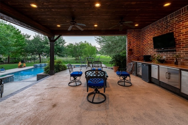 view of patio featuring ceiling fan, exterior kitchen, and an outdoor pool