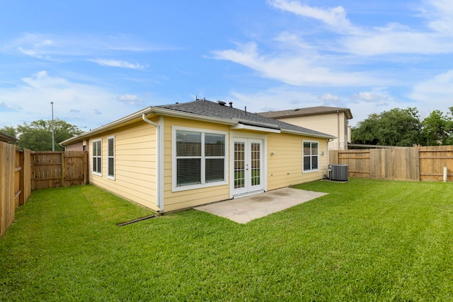 rear view of house with central air condition unit, a fenced backyard, a patio area, french doors, and a lawn