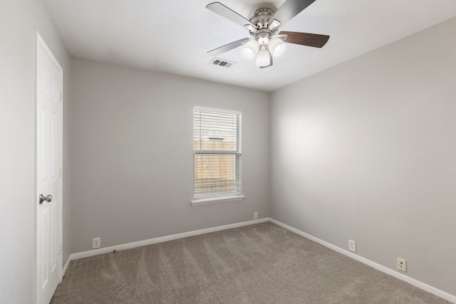 carpeted spare room with visible vents, a ceiling fan, and baseboards