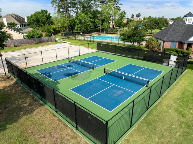 view of tennis court featuring fence and a yard