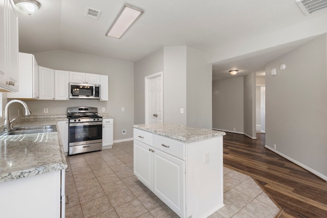 kitchen featuring appliances with stainless steel finishes, a sink, visible vents, and a center island