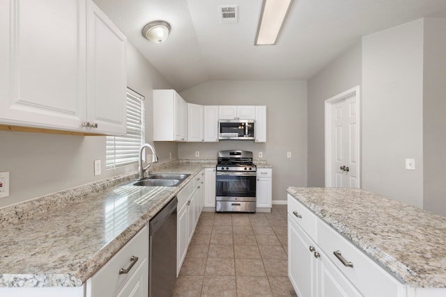 kitchen with visible vents, lofted ceiling, white cabinets, a sink, and appliances with stainless steel finishes