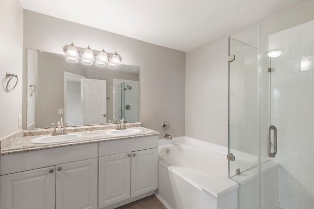 bathroom featuring double vanity, a sink, a bath, and a stall shower