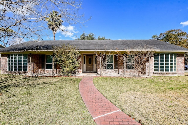 view of front of house featuring brick siding, a shingled roof, a front lawn, and covered porch