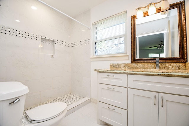 full bathroom featuring vanity, a tile shower, toilet, and marble finish floor