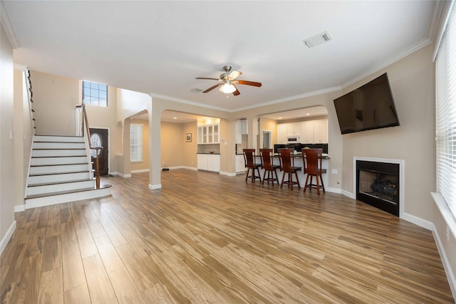 living room with visible vents, arched walkways, stairs, and a ceiling fan