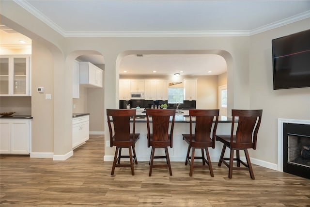 dining area with baseboards, ornamental molding, and wood finished floors