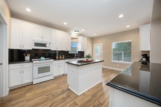 kitchen with dark countertops, white appliances, and white cabinetry