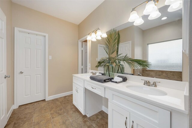 full bathroom with double vanity, baseboards, a notable chandelier, and a sink