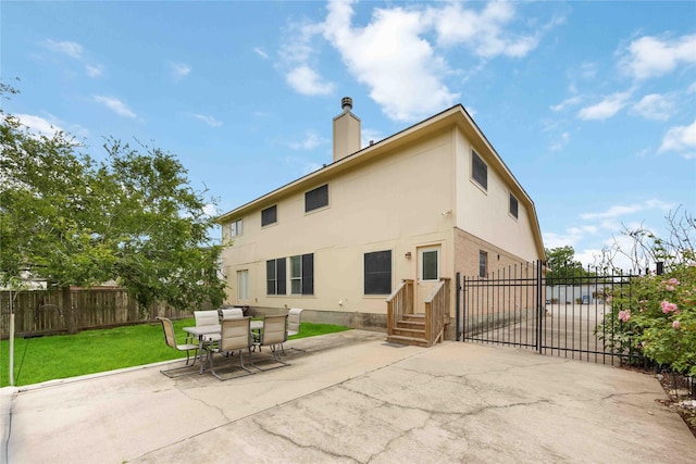 back of house with a yard, a chimney, fence private yard, and a patio area
