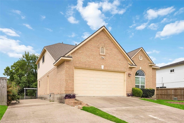 traditional-style home with fence, driveway, roof with shingles, and brick siding