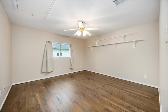 empty room with visible vents, attic access, dark wood finished floors, and baseboards