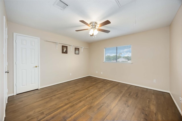 spare room with visible vents, baseboards, attic access, a ceiling fan, and dark wood finished floors