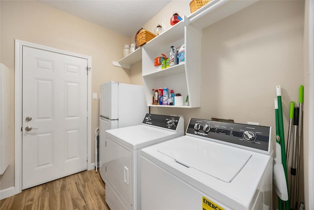 laundry room with laundry area, washing machine and dryer, and light wood-type flooring