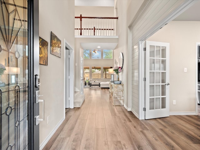 foyer featuring baseboards, wood finished floors, and a high ceiling