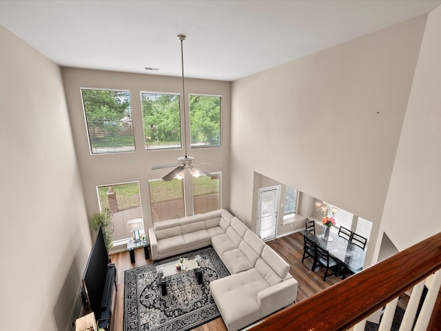 living room featuring a ceiling fan, a towering ceiling, and wood finished floors