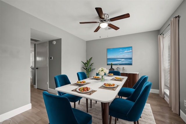 dining space with baseboards, a ceiling fan, light wood-style flooring, and visible vents