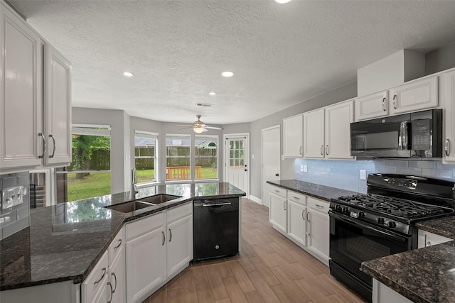 kitchen featuring recessed lighting, a sink, light wood finished floors, and black appliances