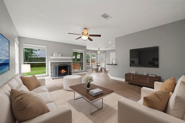 living area with light wood-style floors, ceiling fan, plenty of natural light, and visible vents