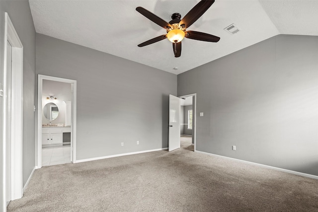 unfurnished bedroom with visible vents, carpet flooring, ensuite bath, and lofted ceiling