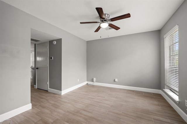 spare room with a ceiling fan, baseboards, visible vents, and wood finished floors