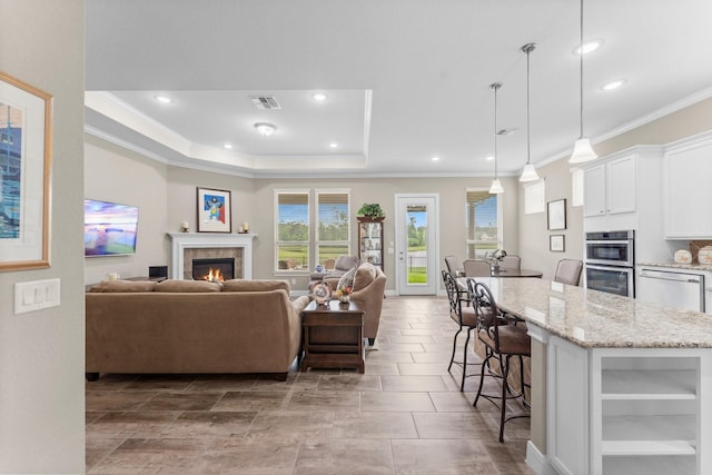 living area featuring visible vents, ornamental molding, recessed lighting, and a fireplace
