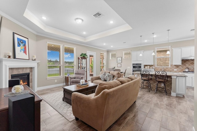living area with a wealth of natural light, a fireplace, ornamental molding, and visible vents
