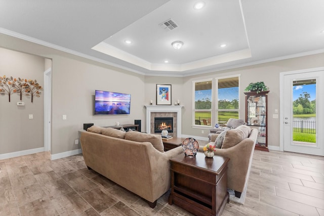 living room with visible vents, crown molding, recessed lighting, a raised ceiling, and a tiled fireplace