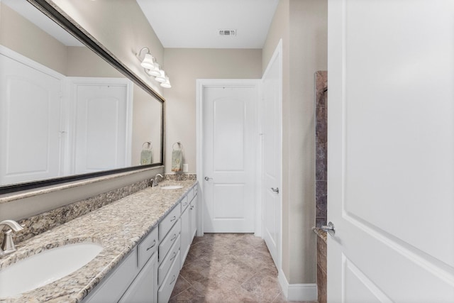 bathroom featuring a sink, baseboards, double vanity, and visible vents