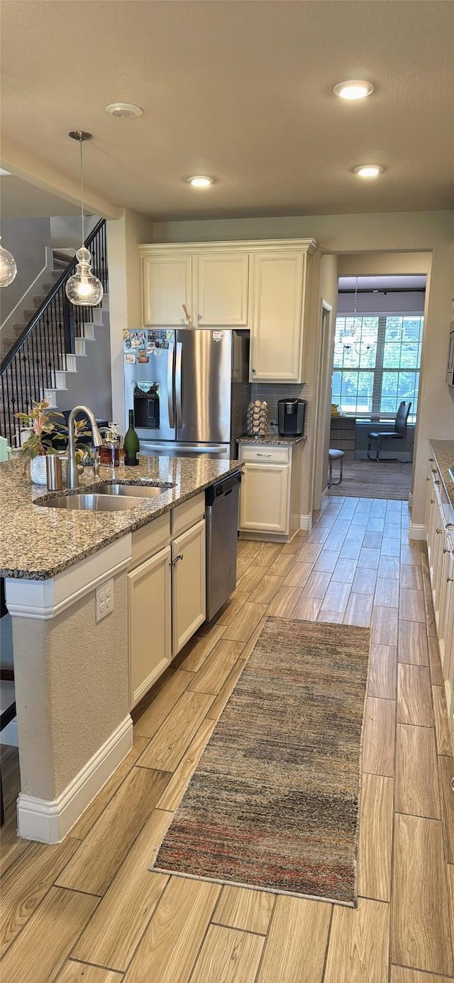 kitchen with light wood-type flooring, white cabinetry, a sink, stone counters, and stainless steel appliances
