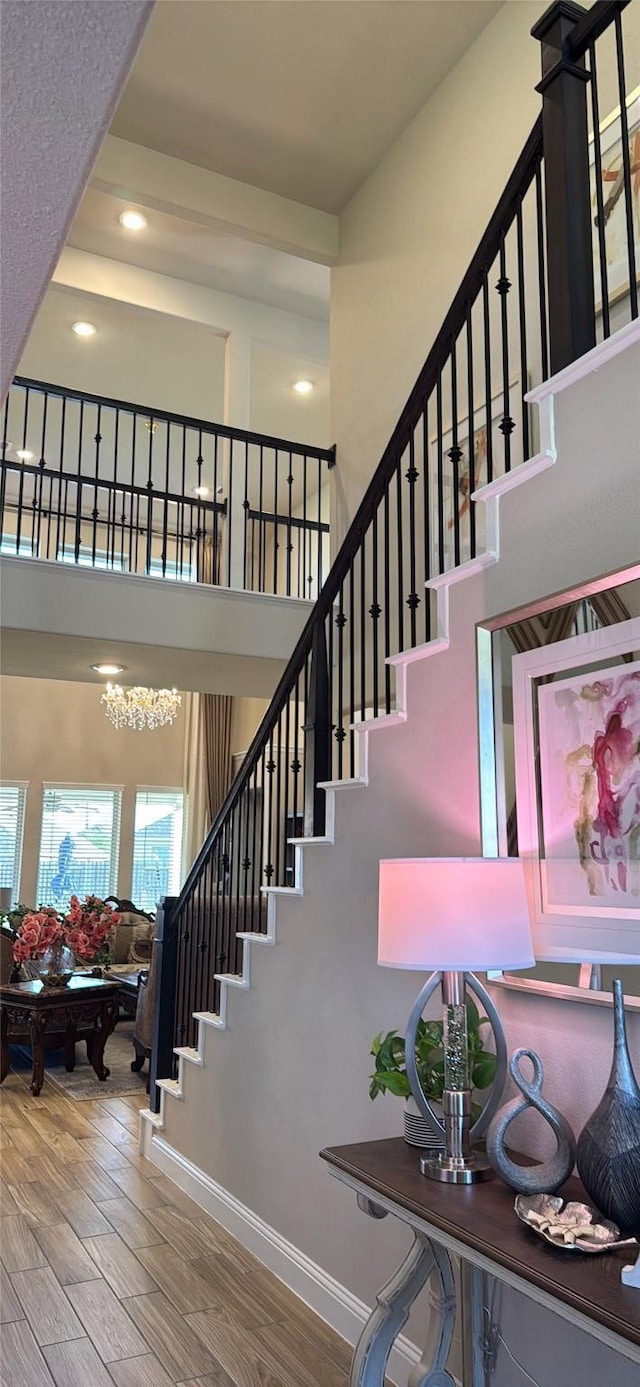 stairs featuring recessed lighting, baseboards, wood finished floors, and a towering ceiling