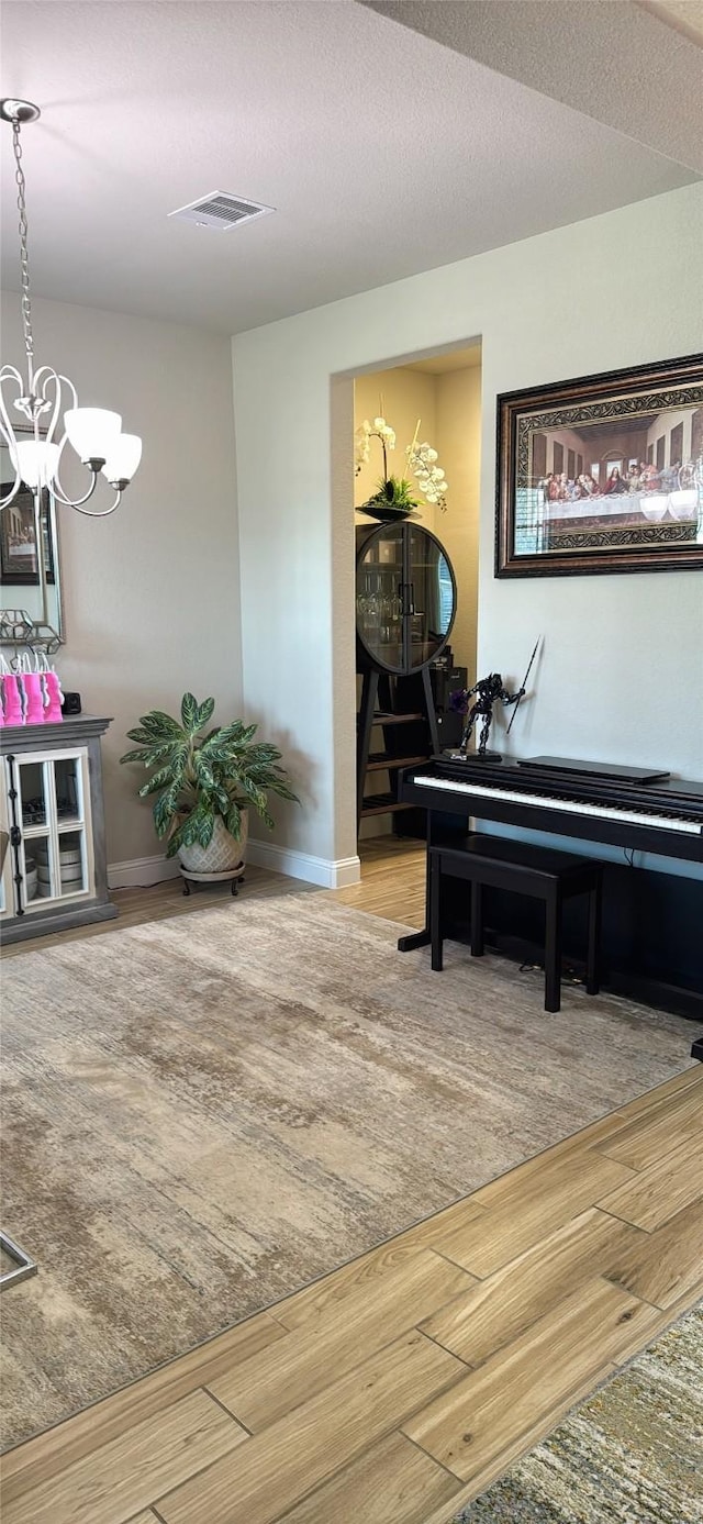 living area featuring visible vents, baseboards, wood finished floors, and a chandelier
