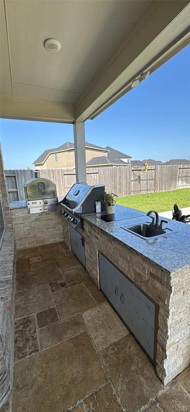 view of patio with an outdoor kitchen, a sink, a fenced backyard, and area for grilling