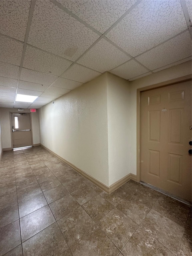 interior space with baseboards, a drop ceiling, and tile patterned floors