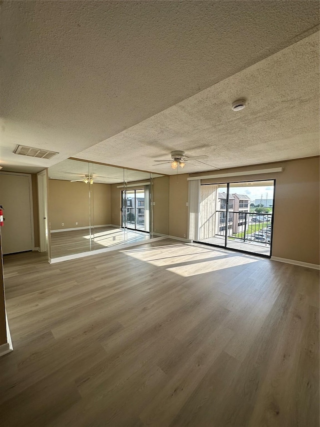 unfurnished room featuring a textured ceiling, baseboards, visible vents, and wood finished floors