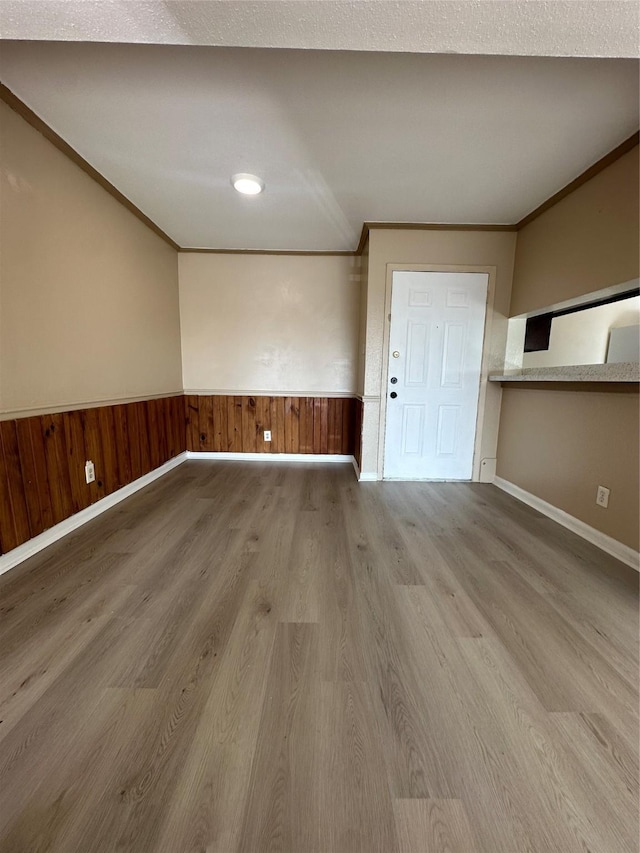 spare room with baseboards, ornamental molding, wainscoting, and wood finished floors