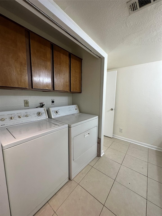 clothes washing area featuring cabinet space, baseboards, light tile patterned floors, visible vents, and washer and clothes dryer